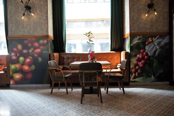Un restaurante con zona de cabinas, una mesa con sillas y un mural de frutas en la pared.