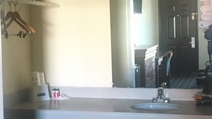 Casa de banho de hotel com lavatório, espelho, porta-toalhas e porta de acesso ao quarto.