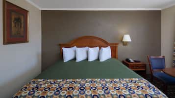 A hotel room with a bed, a nightstand, a chair, and a lamp.