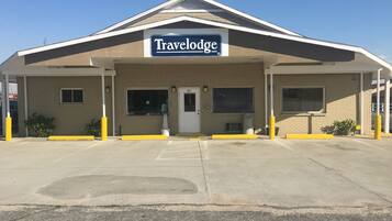 A Travelodge hotel with a simple facade, a prominent sign, and a parking lot in front.