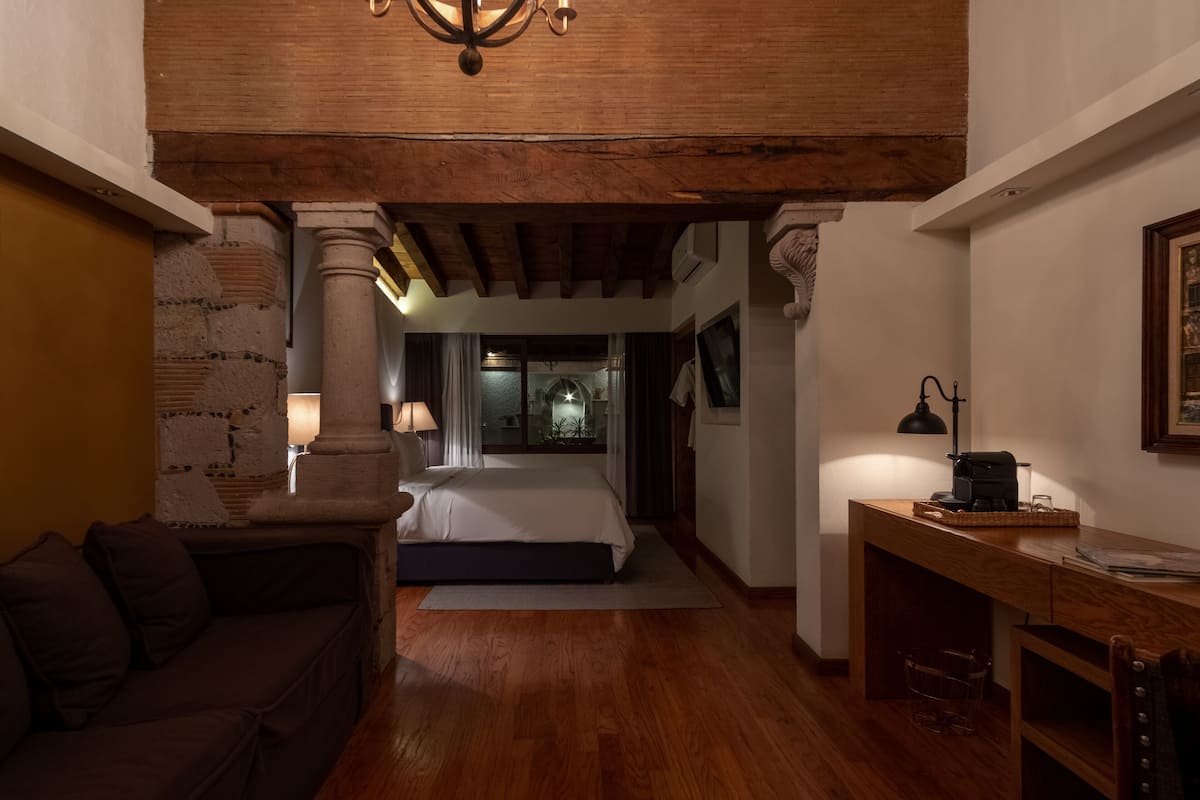 Ein gemütliches Schlafzimmer mit Holzbalkendecke, einem Bett, einem Schreibtisch und einem Nachttisch.
