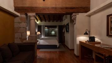 Un dormitorio acogedor con techo de madera, una cama, un escritorio y una mesita de noche.