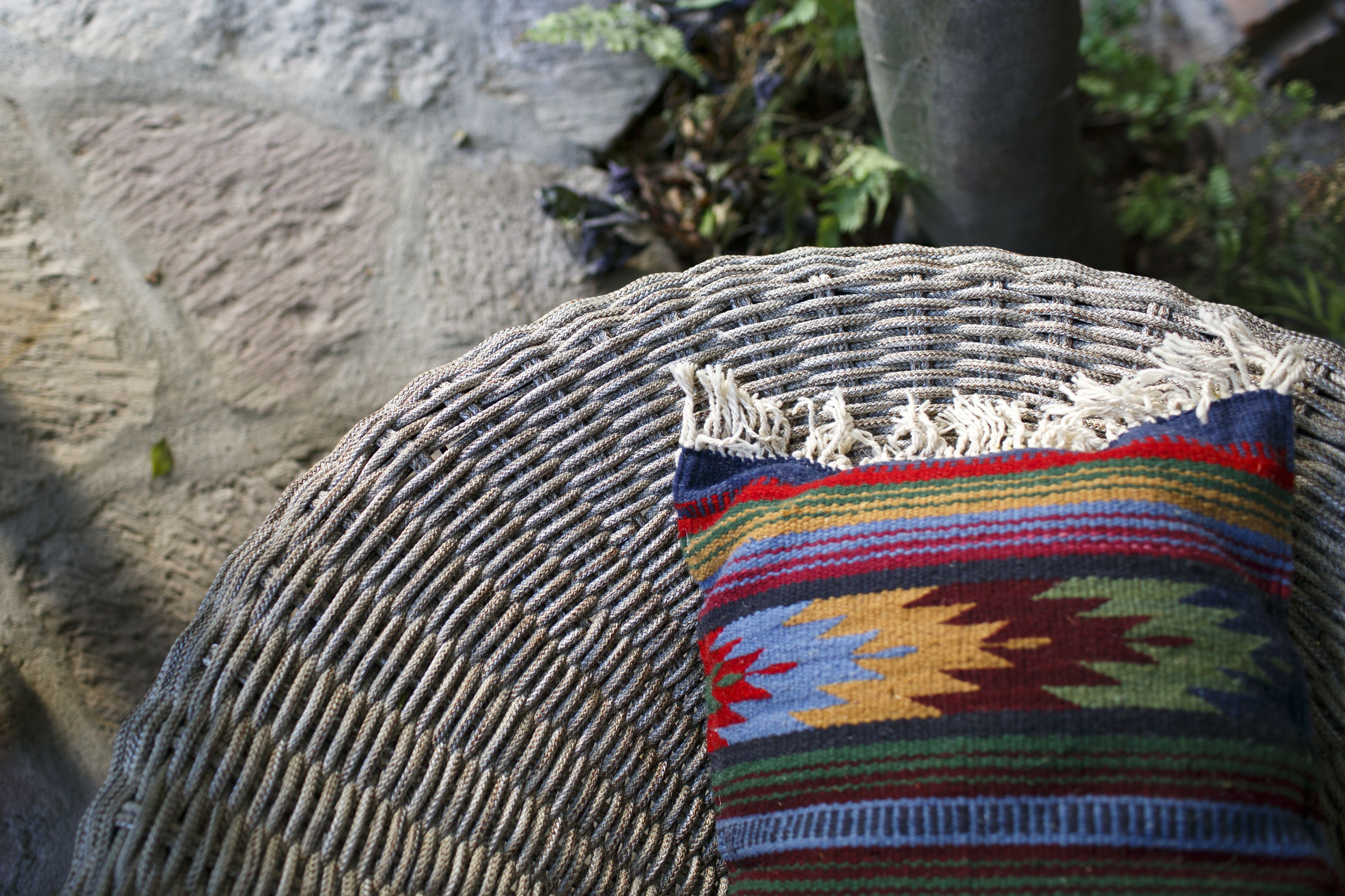 A woven chair with a colorful cushion.