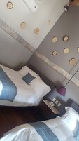 Een hotelkamer met twee bedden, een nachtkastje, een lamp en een wand met decoratieve borden.