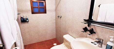 Baño con ducha, inodoro, lavabo y ventana.