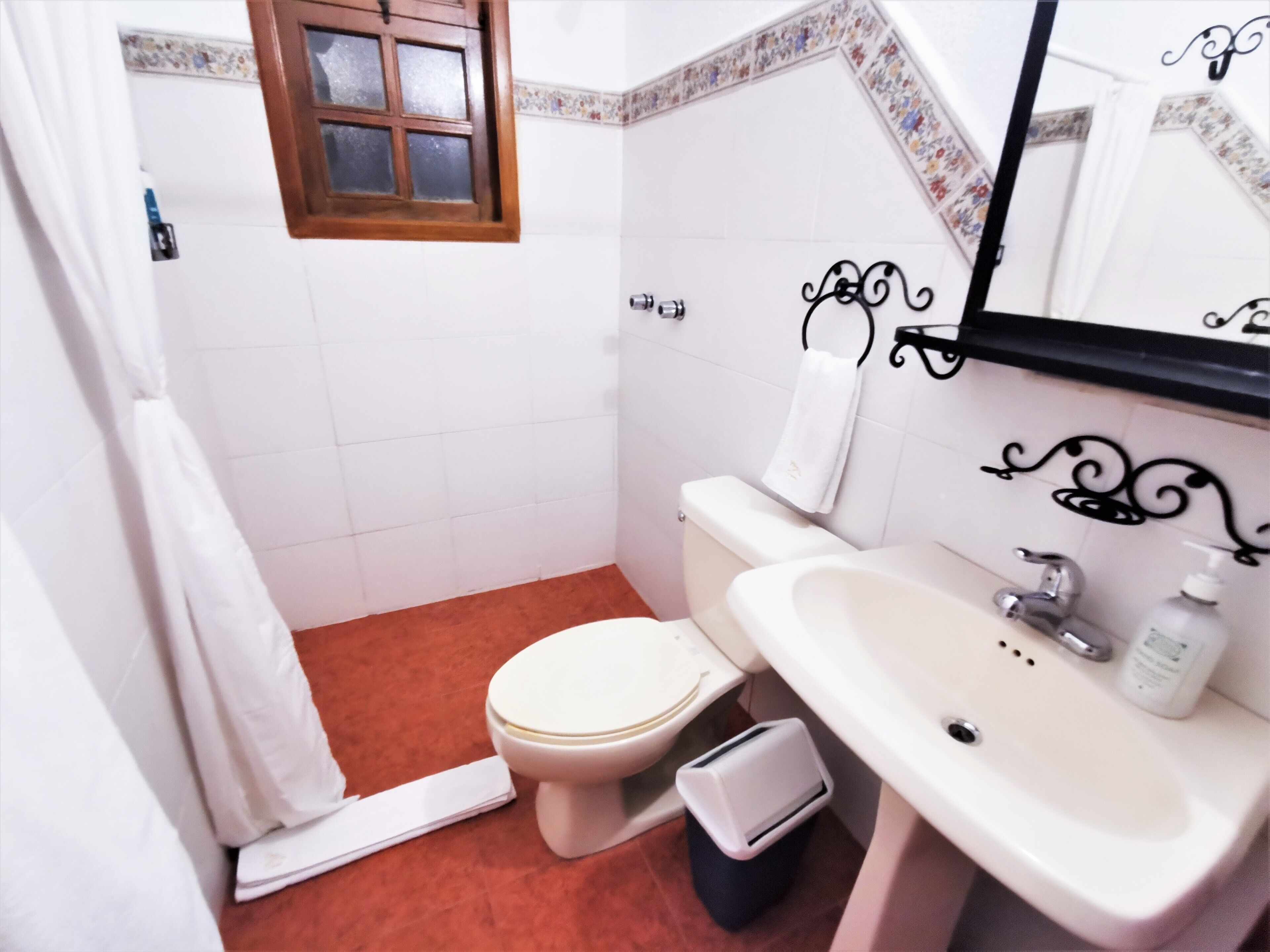 A small bathroom with a toilet, sink, and a window.