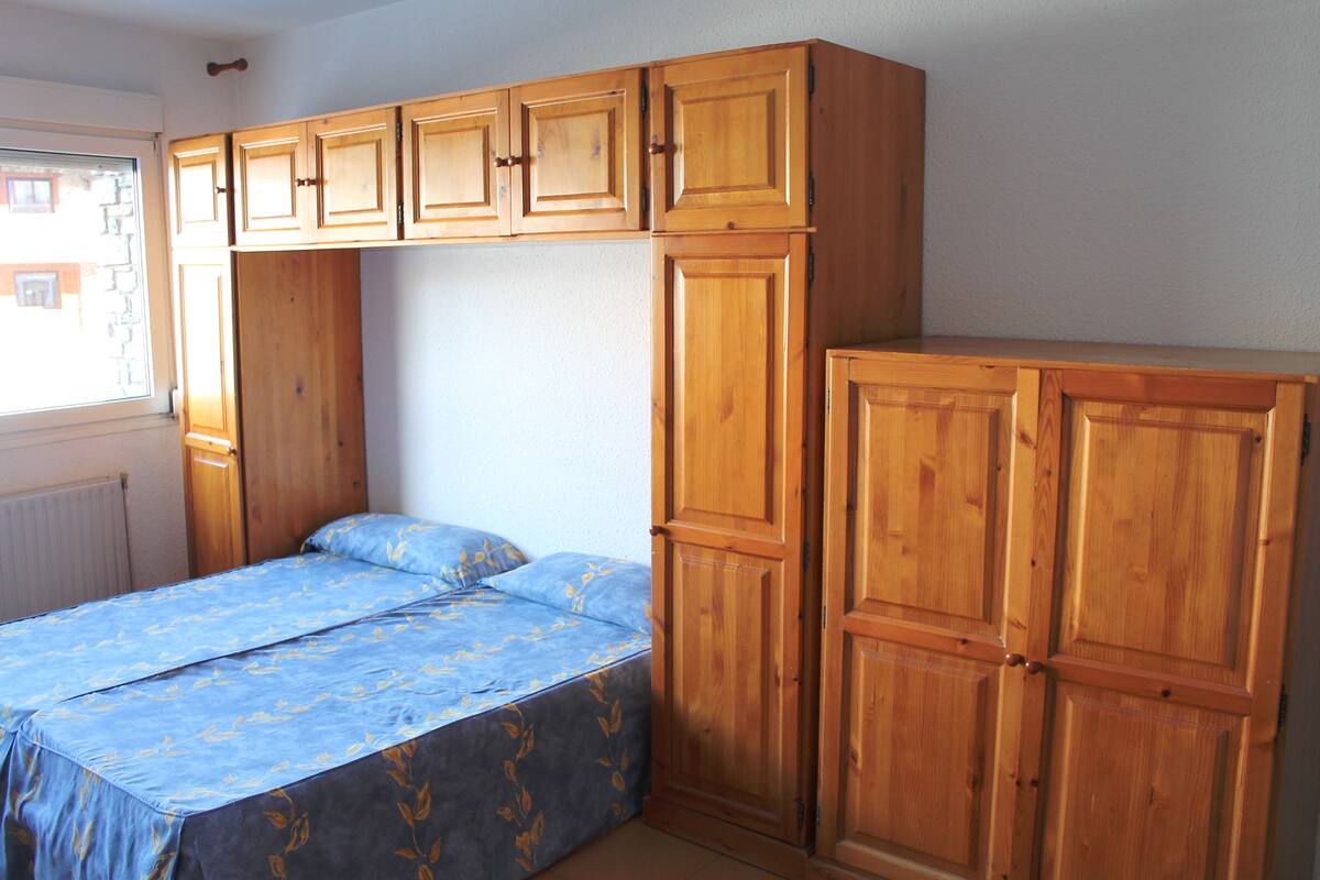 Une chambre à coucher avec un lit, une armoire en bois et une fenêtre.