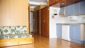 Um espaço compacto com cozinha compacta, um armário de madeira, micro-ondas e máquina de lavar louça branca.