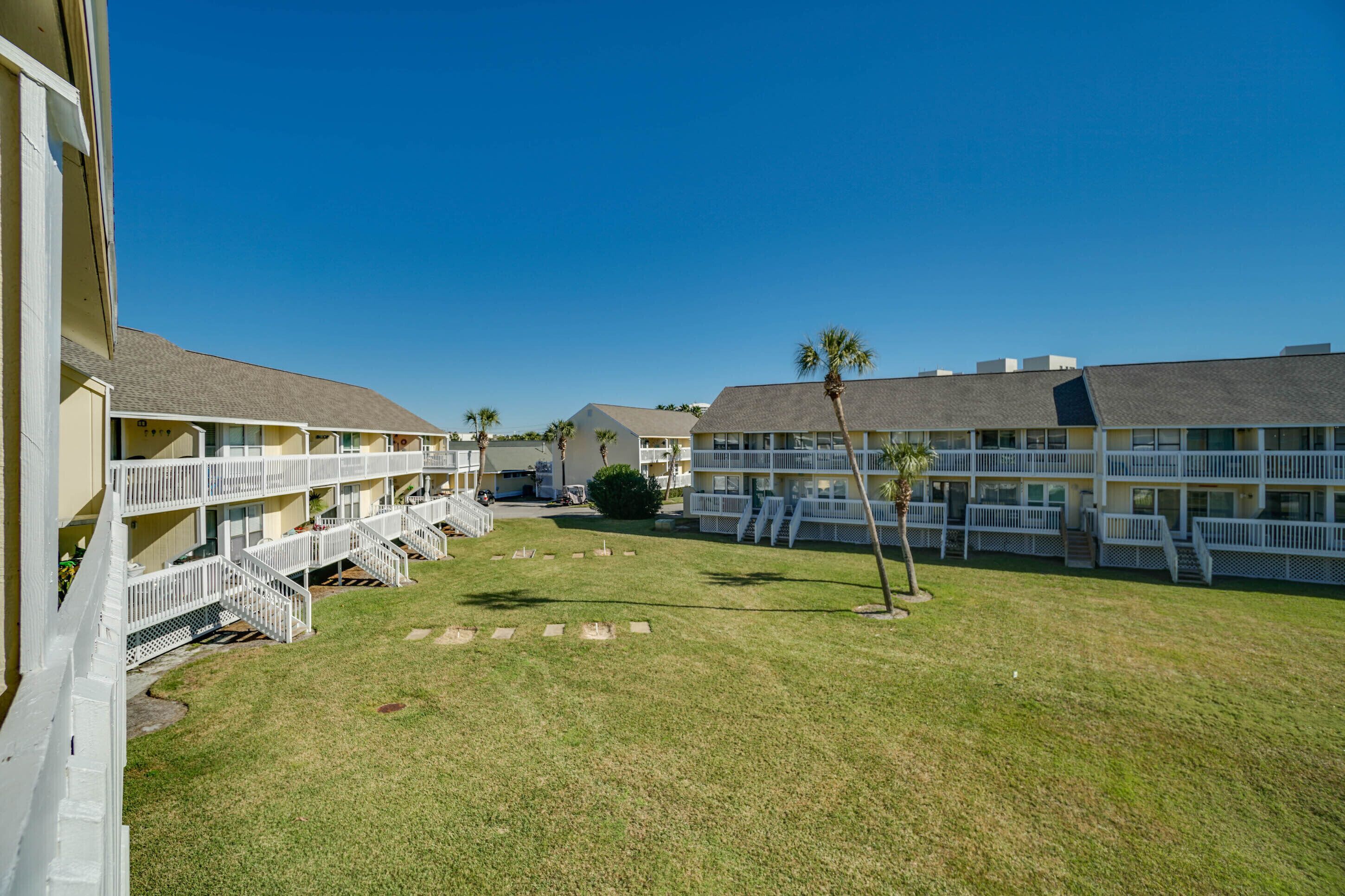 A hotel with multiple-story buildings, outdoor balconies, and a well-maintained lawn.