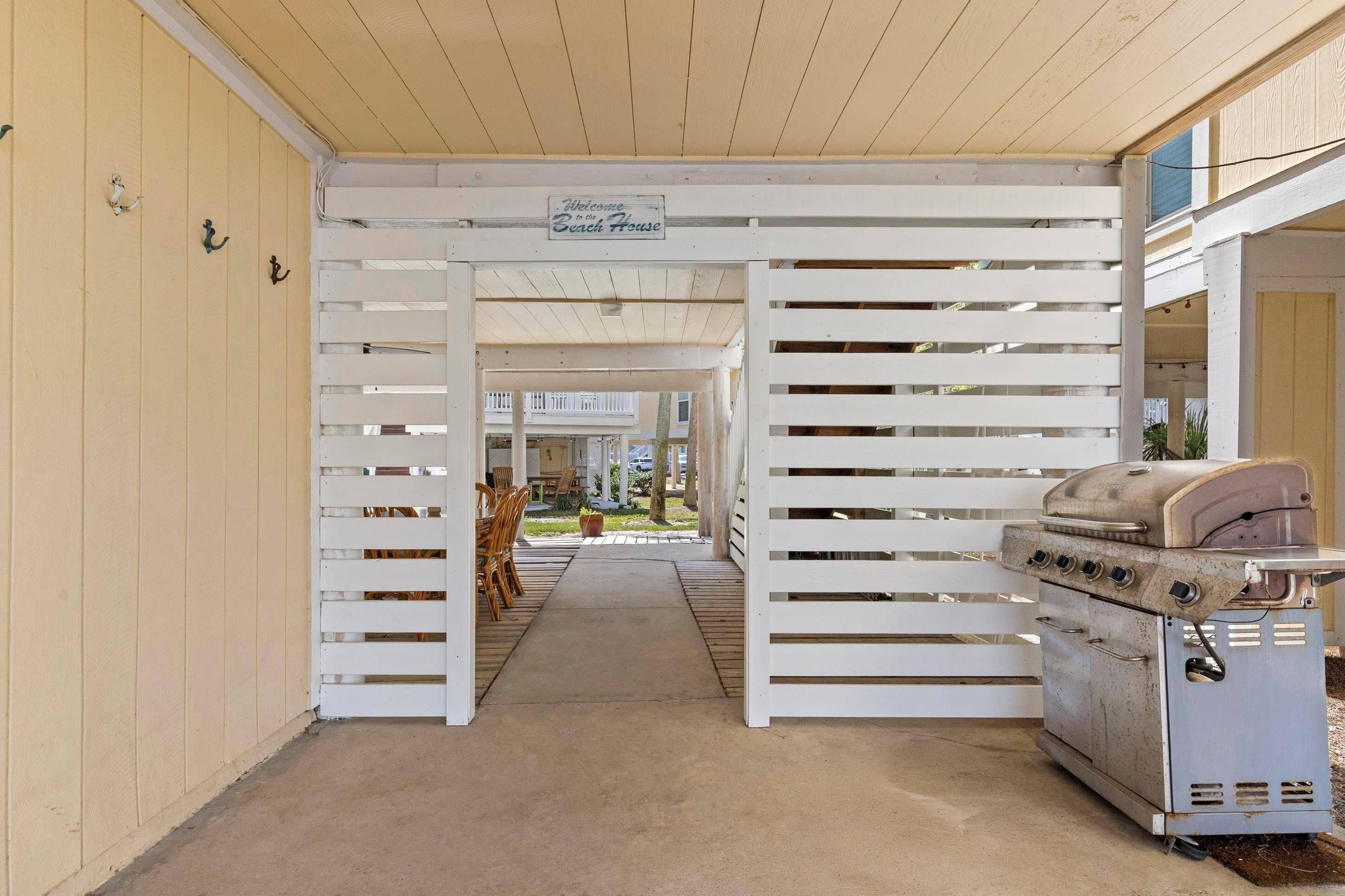 Un espacio al aire libre cubierto con una parrilla, listones de madera y un letrero que dice 'Welcome to the Beach House'.