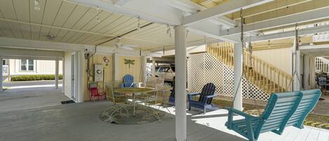 A covered outdoor area with a wooden deck, a swing, and a table with chairs.