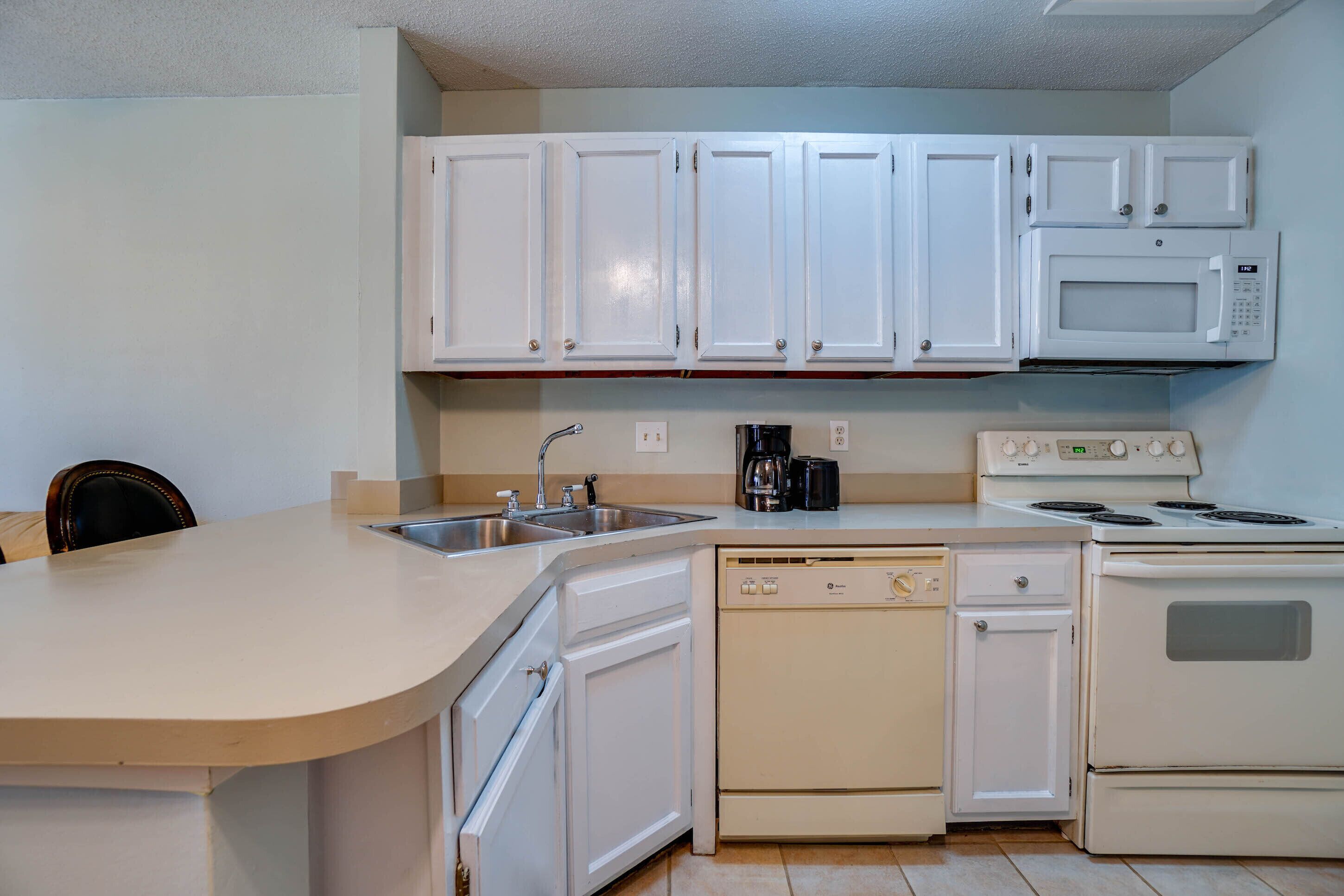 A kitchen with white cabinets, a dishwasher, a stove, and a microwave.