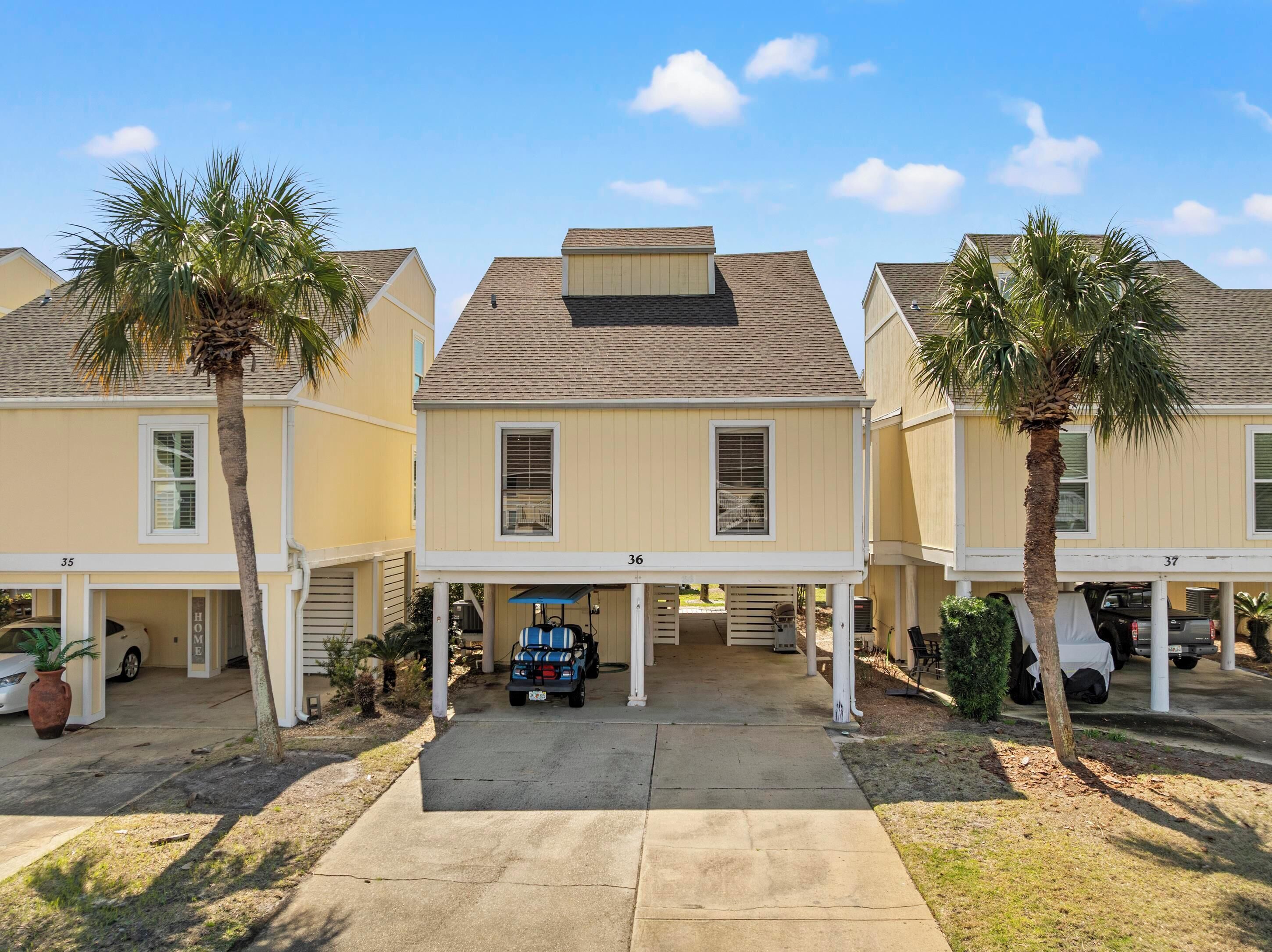 A row of two-story yellow buildings with a covered driveway, numbered 35 to 37, and palm trees in front.