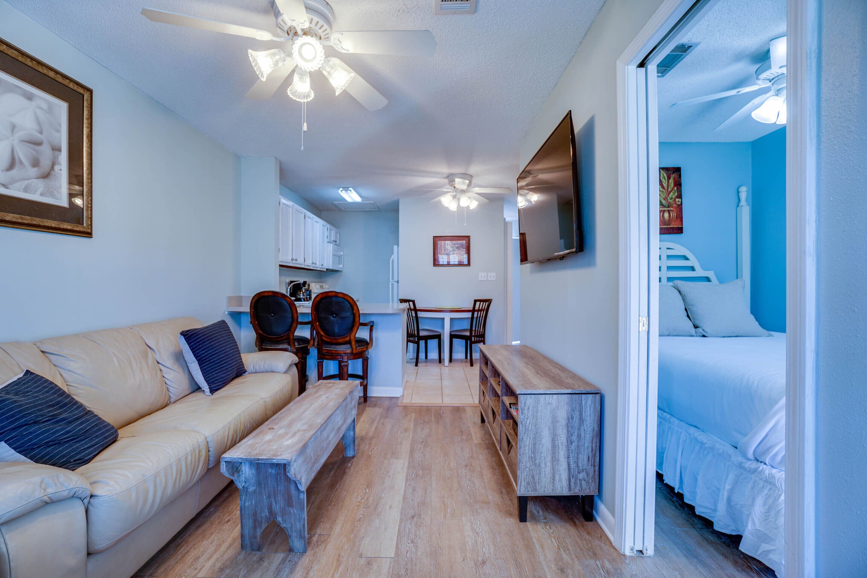 A compact living space with a sofa, a dining table with chairs, a small kitchen area, and a bedroom with a bed.