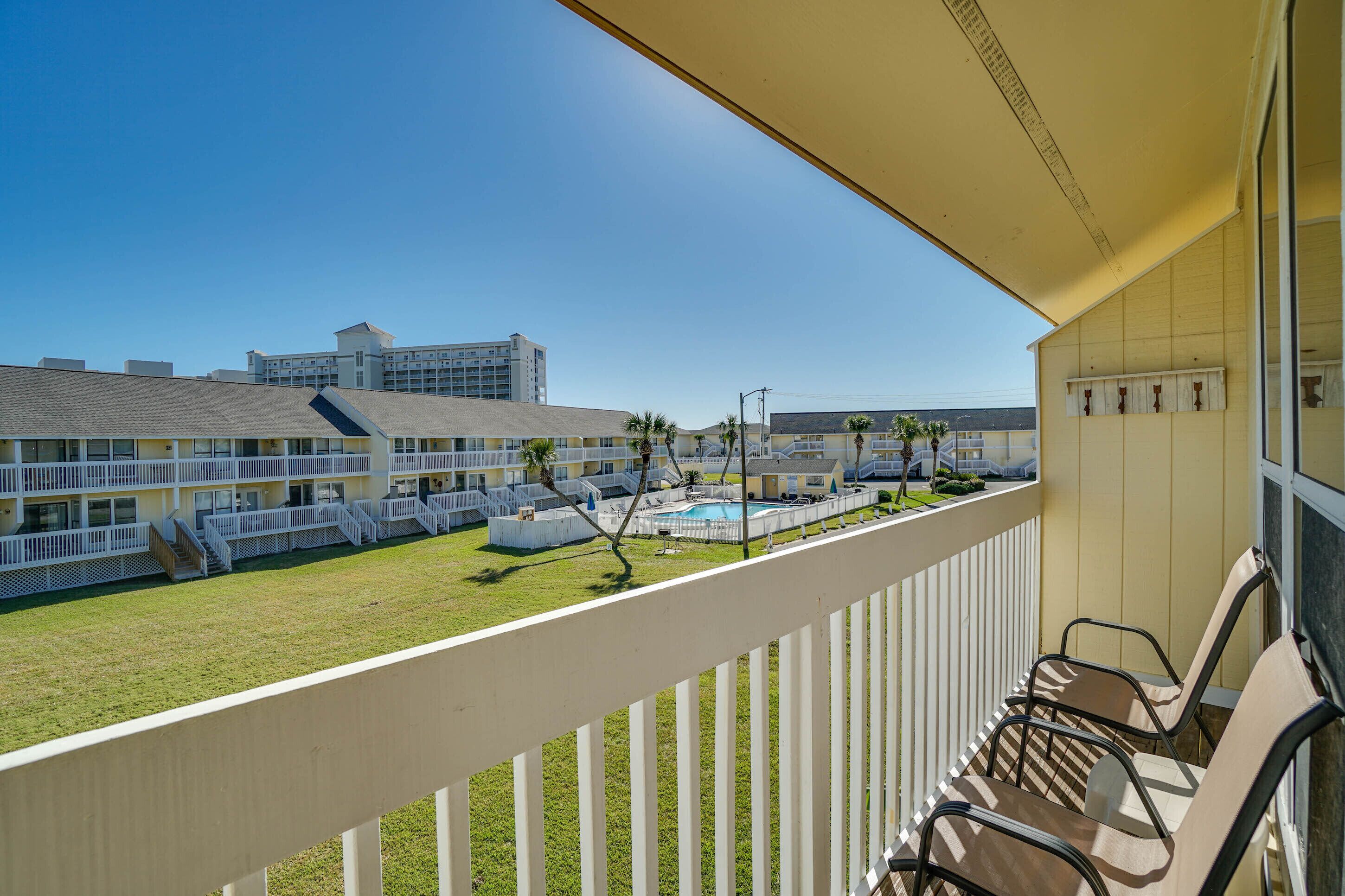 A hotel balcony with a view of a swimming pool and adjacent buildings.