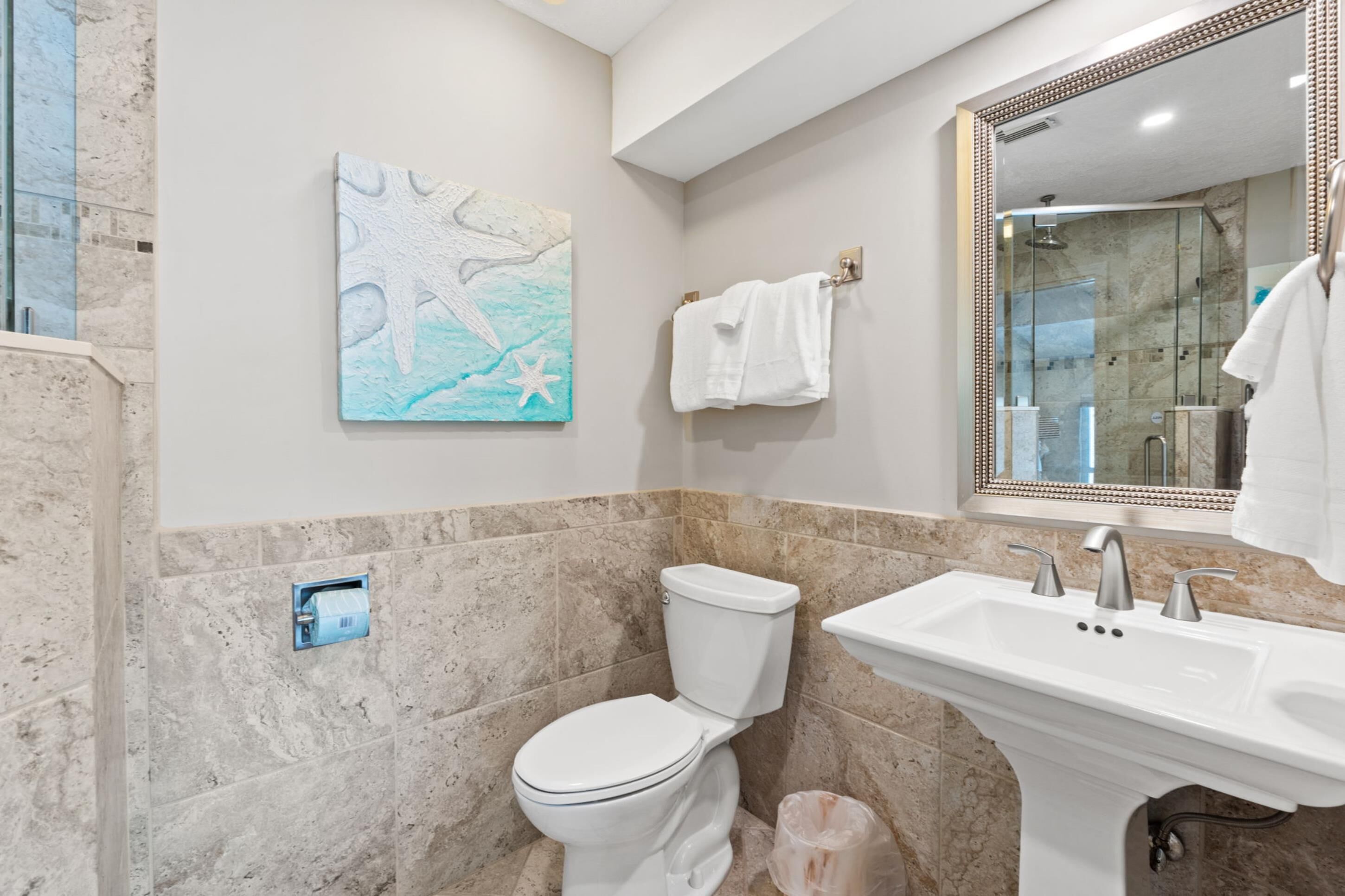 Une salle de bain équipée de toilettes, d’un lavabo et d’une douche à parois en verre.