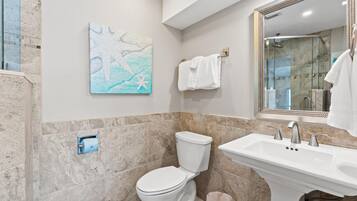 Une salle de bain équipée de toilettes, d’un lavabo et d’une douche à parois en verre.