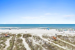 A beach with white sand, clear blue water, and a wooden fence. - Sailfish Townhomes by Panhandle Getaways (Panama City Beach)