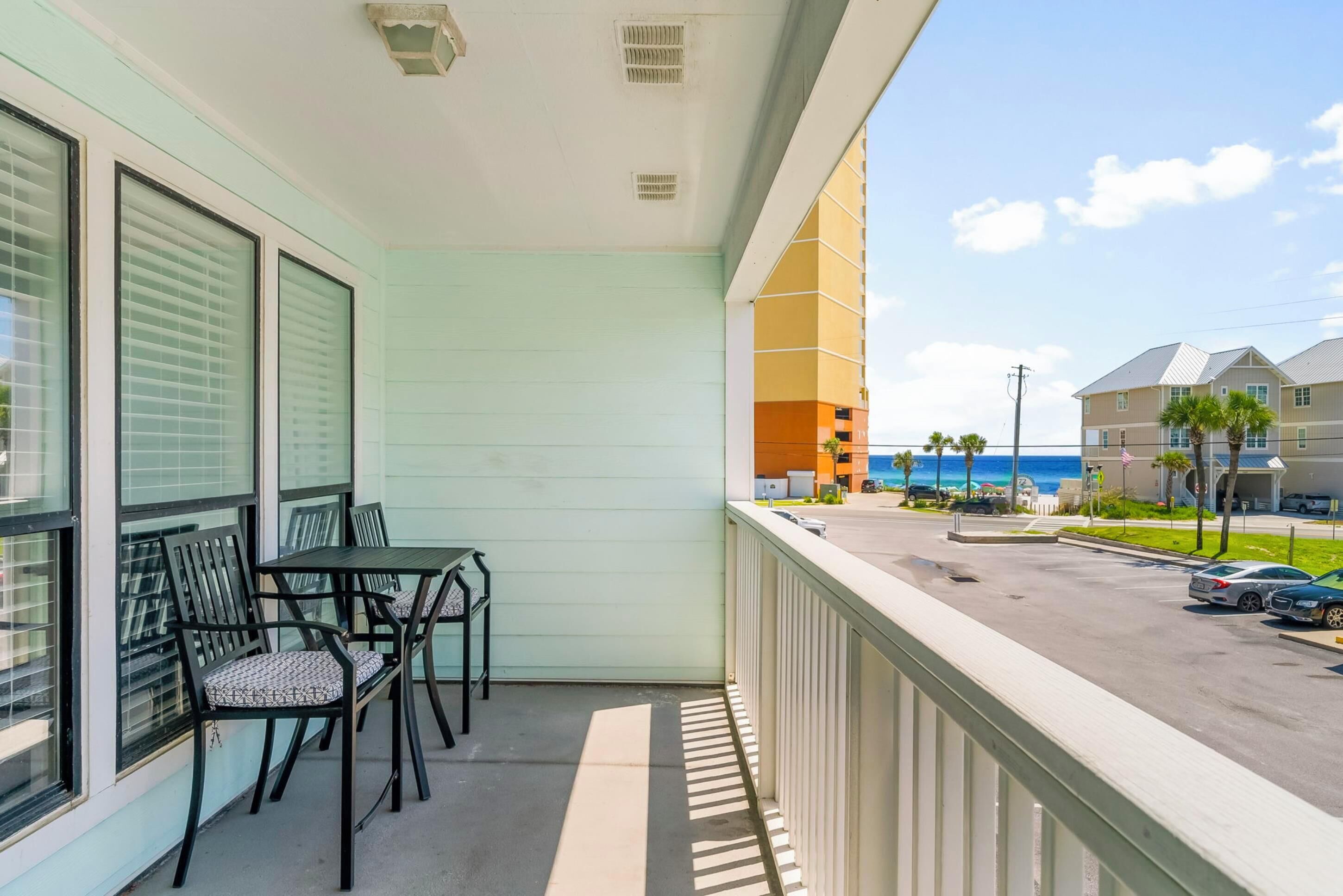 A balcony with a view of the ocean and a parking area.