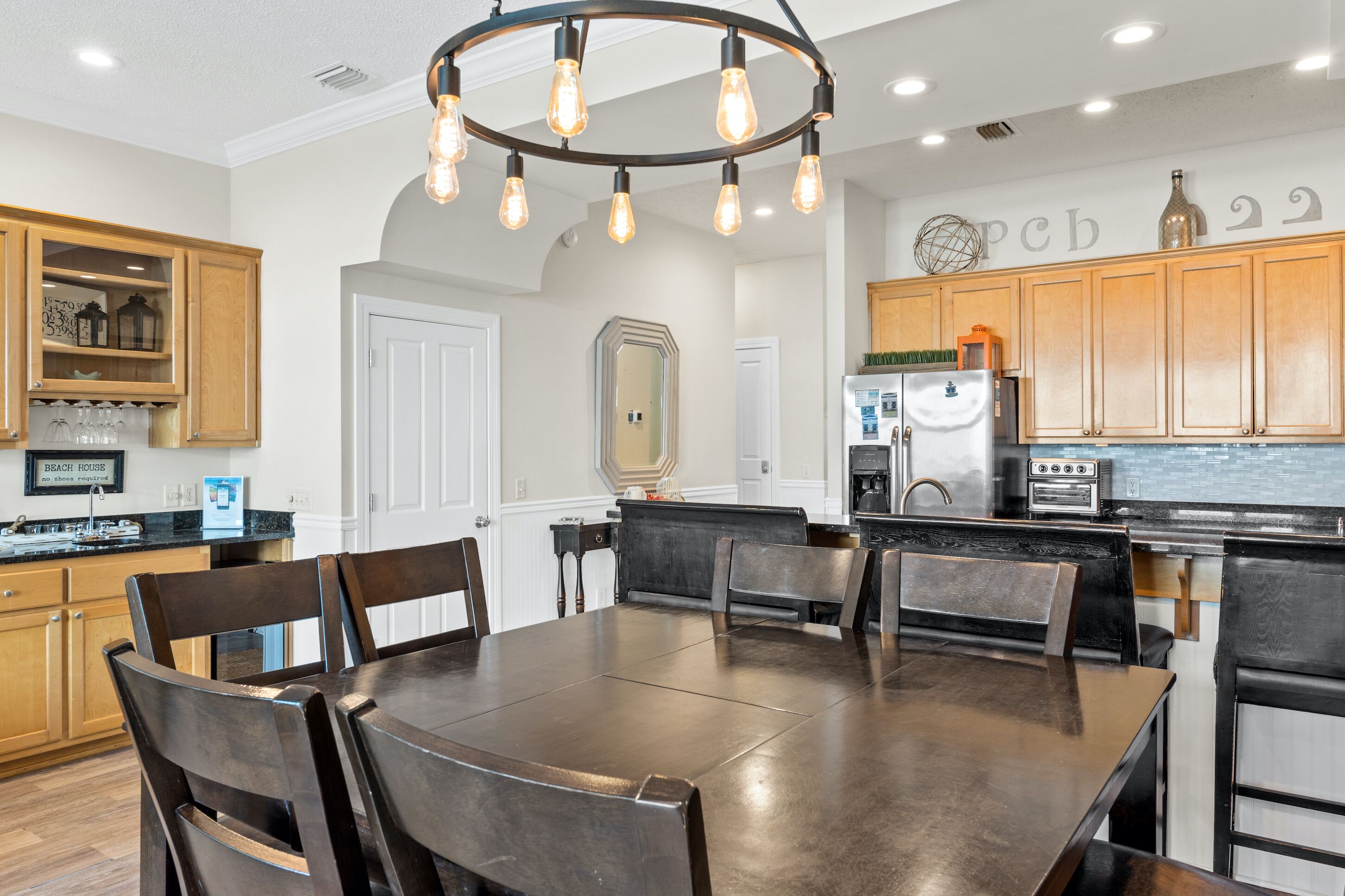 A modern kitchen with wooden cabinets, a dining table, and a chandelier.
