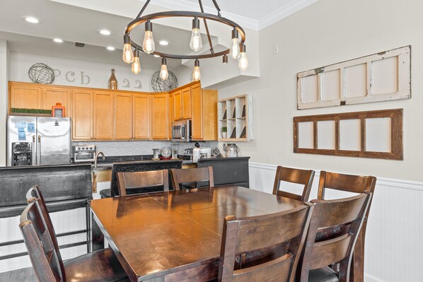 A modern kitchen with wooden cabinets, a central island, and a dining area with a large wooden table and chairs.