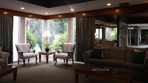 A spacious living room with a large window, a sofa, two armchairs, and a coffee table.