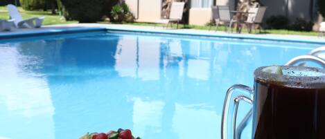 Una mesa con nachos y un vaso de cerveza junto a una piscina.