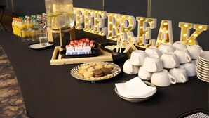 A buffet table with a large illuminated sign reading "FEARREAZ," a variety of beverages, cookies, and white ceramic cups and saucers.