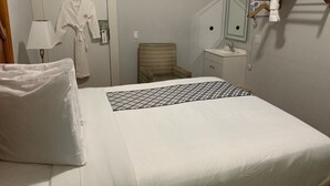 A hotel room with a bed, a chair, a small table, a sink, and a mirror. - Warfield Hotel (San Francisco)