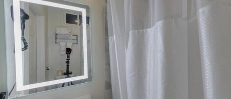 A bathroom with a large mirror, a sink, and a shower curtain.