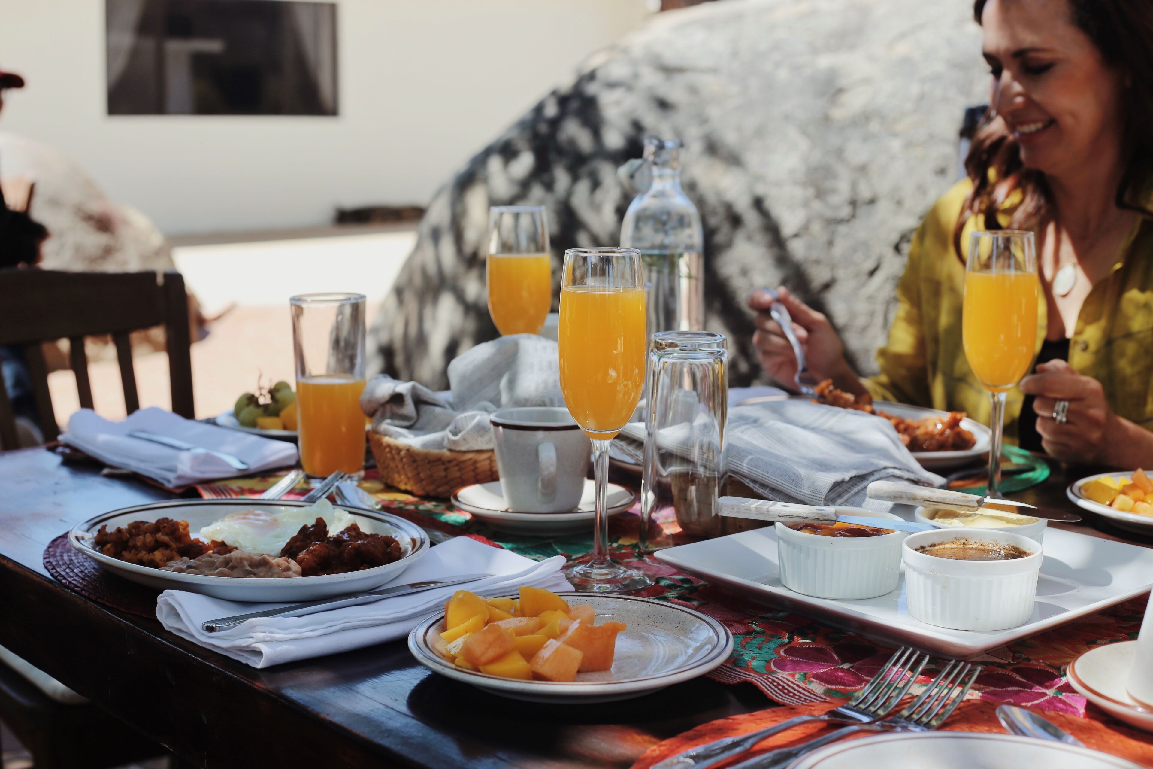 A breakfast table with plates of food, glasses of orange juice, and a bottle of water.