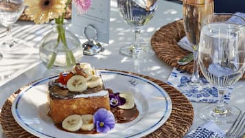 A dessert plate with bananas and chocolate sauce, surrounded by a wicker basket and a menu.