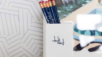 Uma escrivaninha com um bloco de notas branco, três lápis e um porta-canetas com design preto.