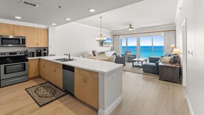 Una cocina moderna con una isla central, un comedor con vistas y una sala de estar con sofá y lámpara.