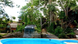 Una piscina envoltada de vegetació exuberant i estructures de fusta.