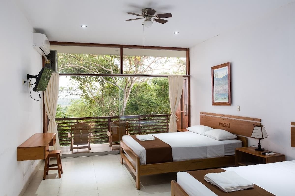 A bedroom with a bed, a desk, a chair, a nightstand, and a ceiling fan.