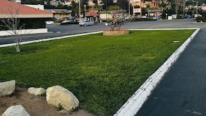 Un motel con techo rojo, estacionamiento y zona verde con rocas.