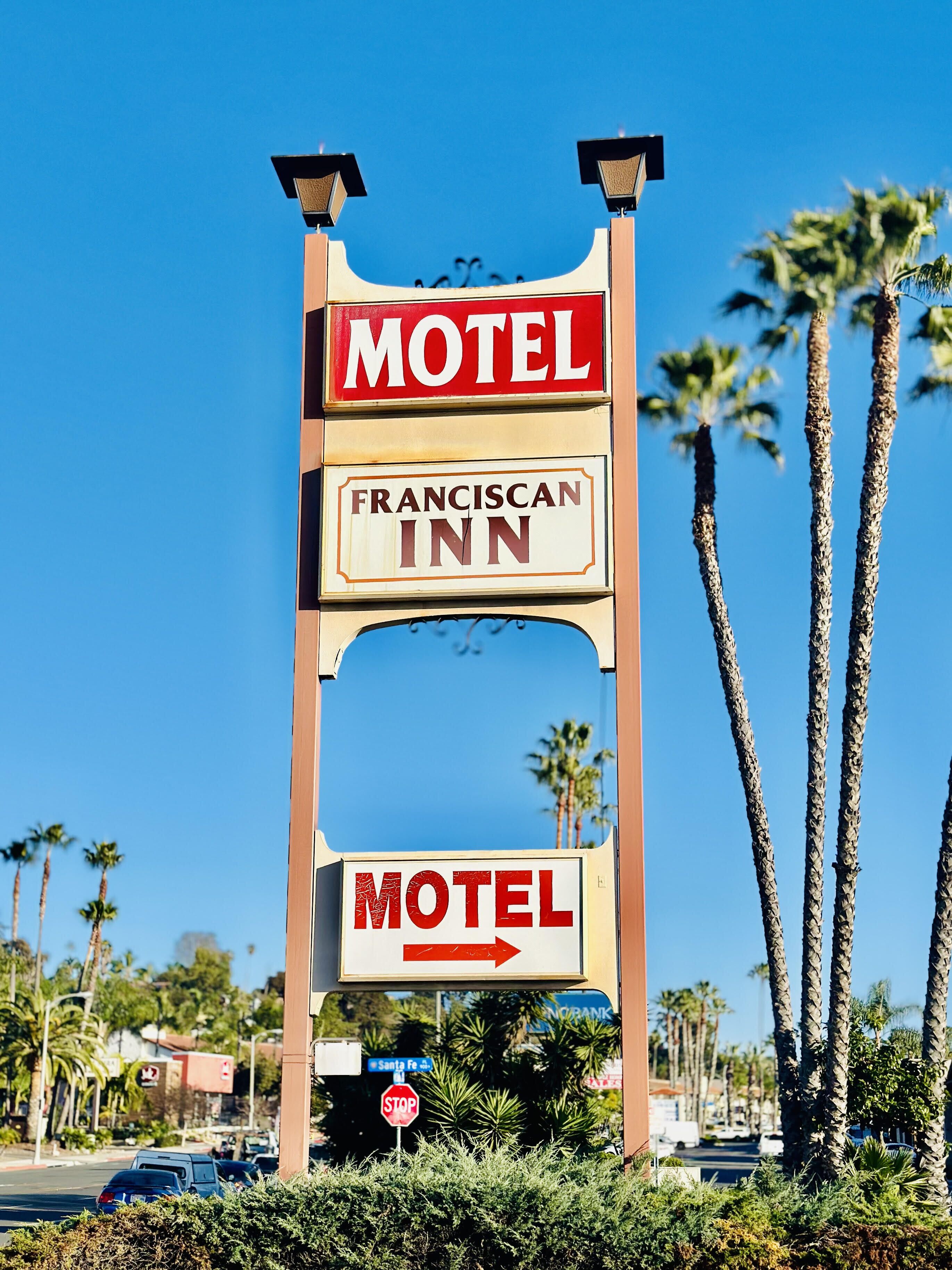 A motel sign with "Motel" and "Franciscan Inn" written on it, and an arrow pointing to the right.