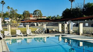Una piscina azul cristalina con sillas de descanso y una valla.