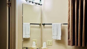 A hotel bathroom with a granite countertop sink, a mirror, two towels, a towel rack, and a curtain.