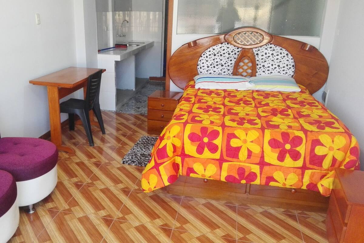 Una habitación con una cama, un escritorio y dos sillas.