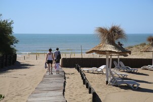 En la playa, sillas reclinables de playa, sombrillas, toallas de playa