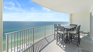 A balcony with a table and chairs, overlooking a beach and the ocean. - Twin Palms Resort by Panhandle Getaways (Panama City Beach)