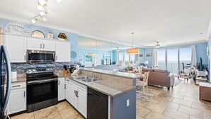 A modern kitchen with stainless steel appliances, a large island with a sink, and a dining area with a view. - Twin Palms Resort by Panhandle Getaways (Panama City Beach)