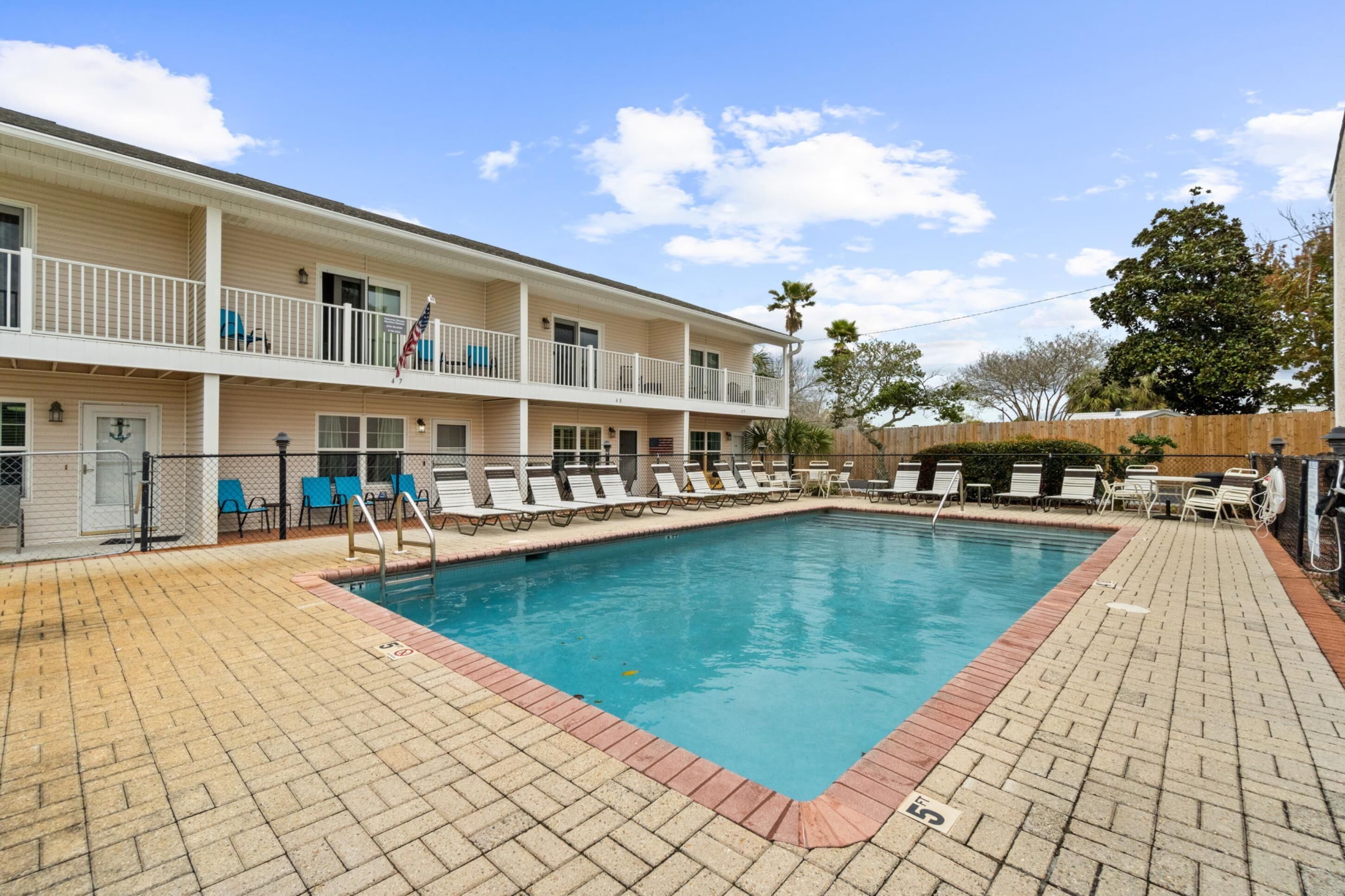 A two-story building with a swimming pool, outdoor seating, and a flag.