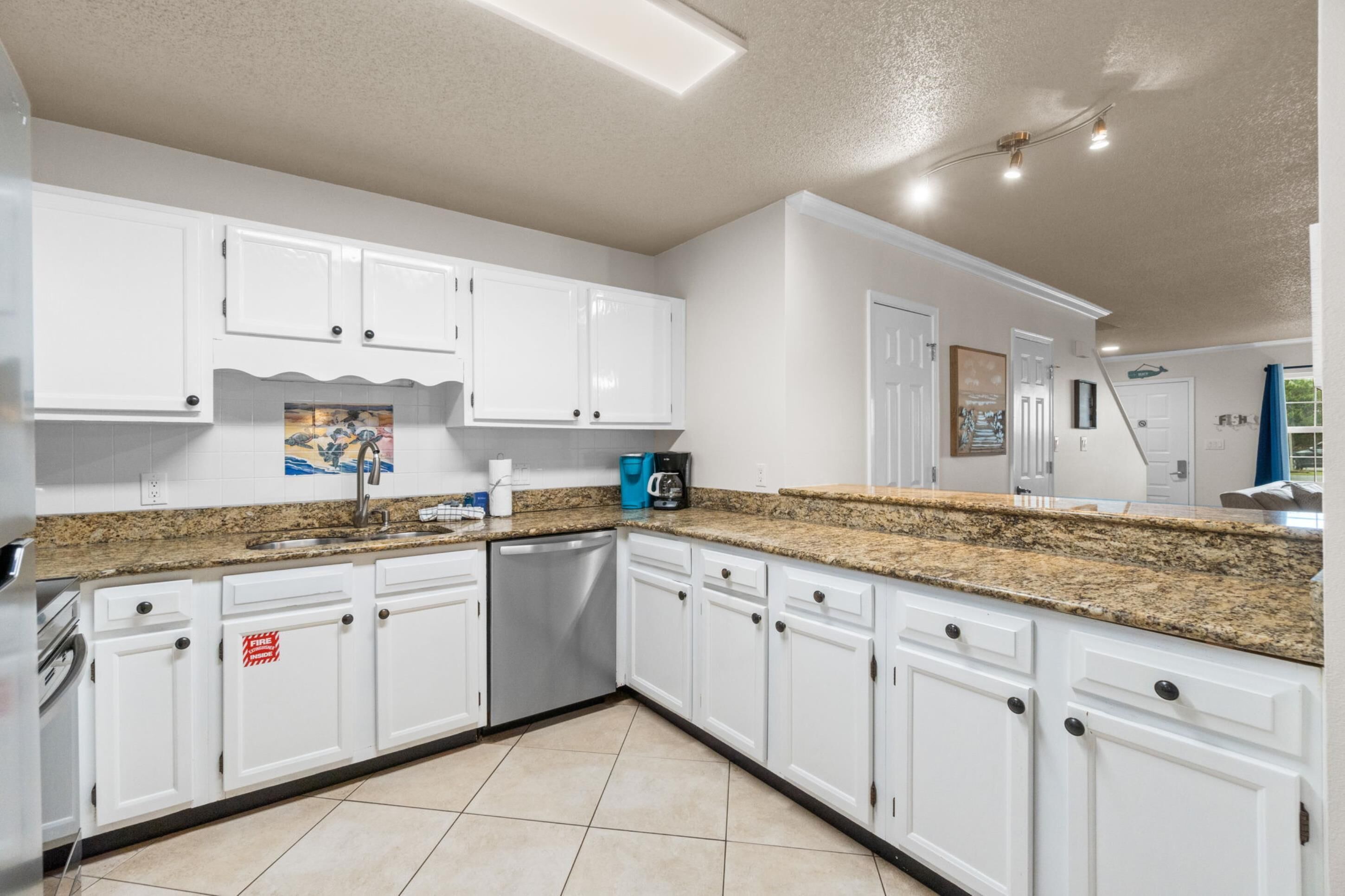 A modern kitchen with white cabinets, granite countertops, and stainless steel appliances.