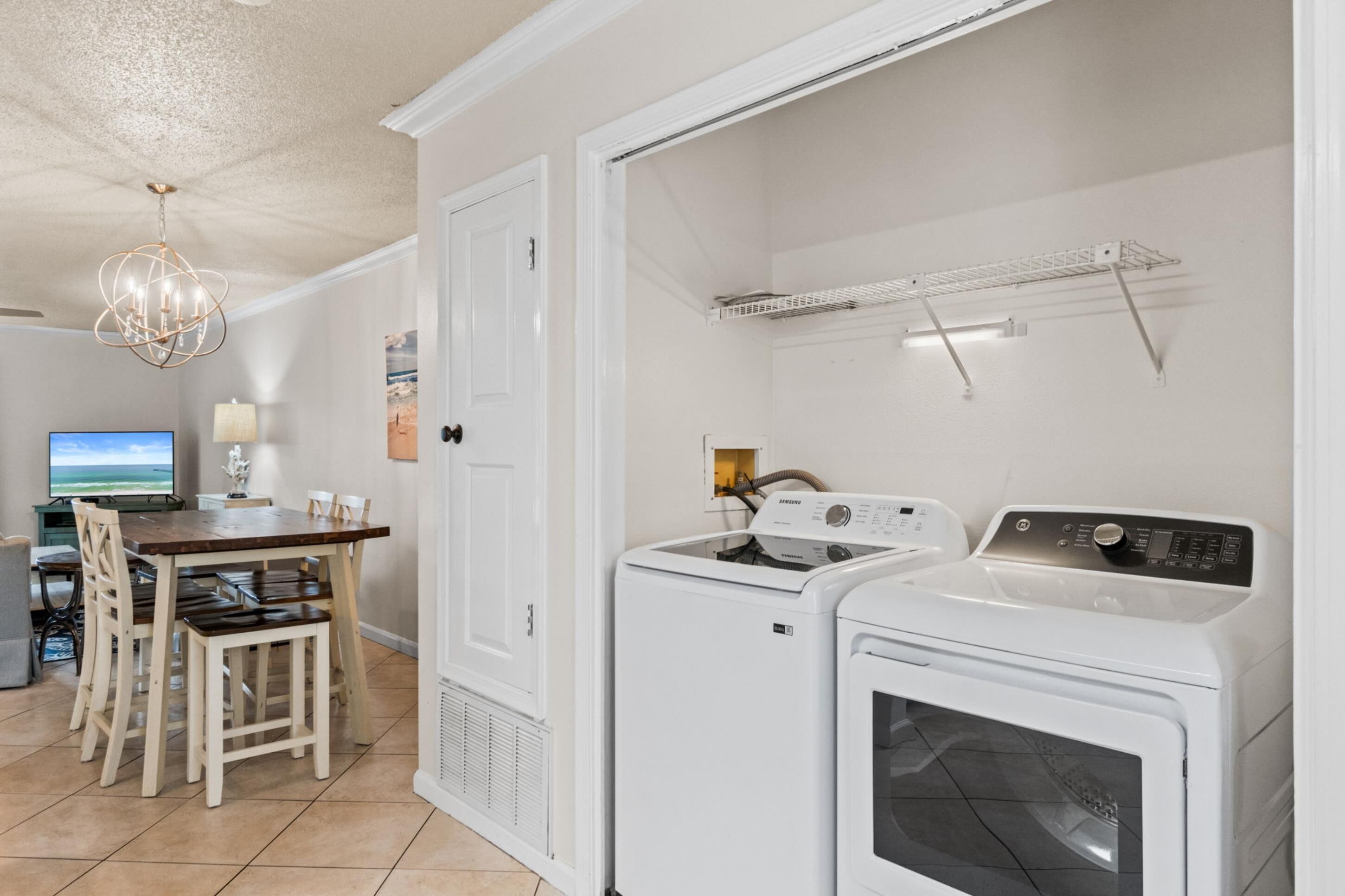 A laundry room with a washing machine, dryer, and a drying rack.