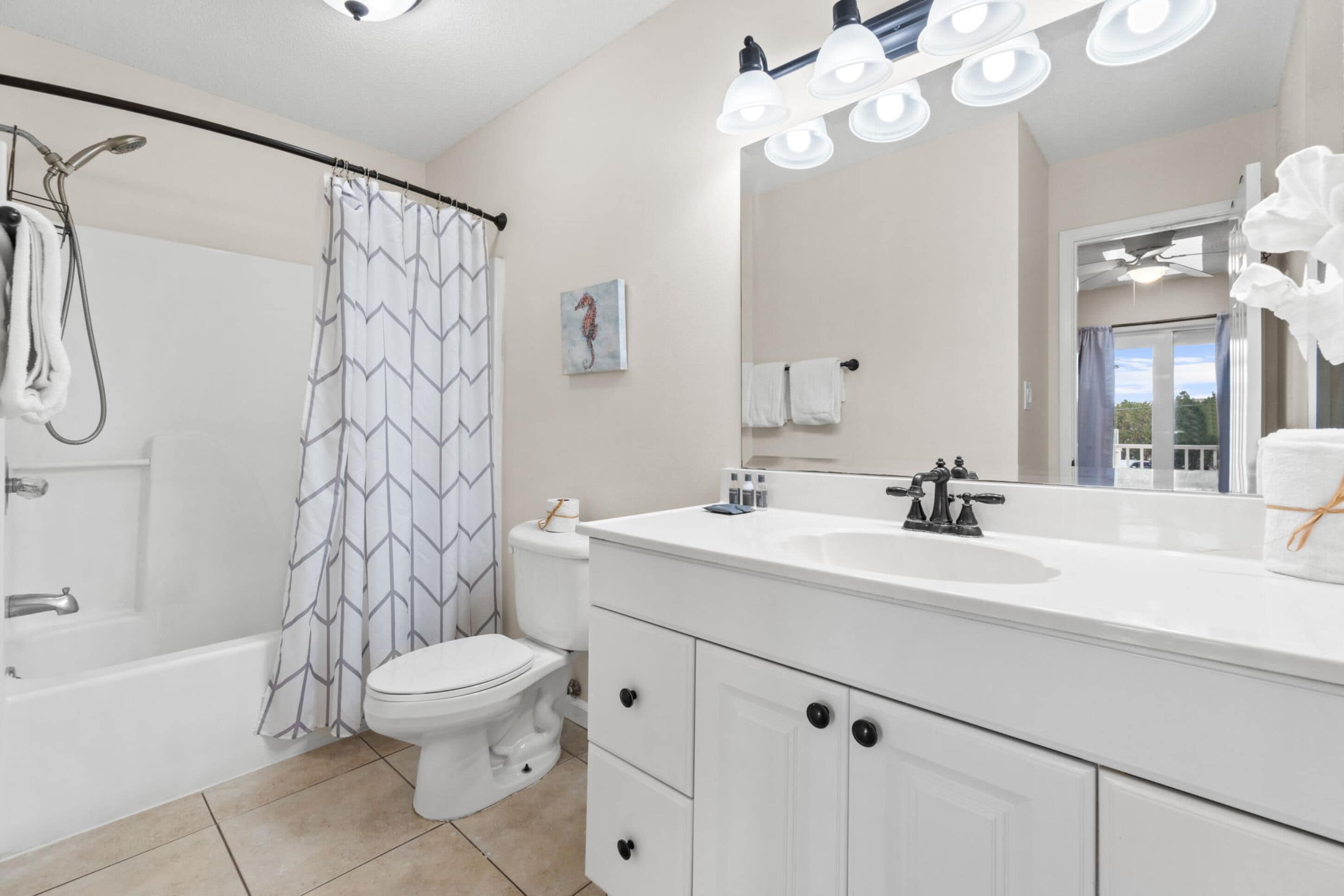 A modern bathroom with a bathtub, toilet, shower, and a large mirror with lights.