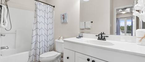 A modern bathroom with a bathtub, toilet, shower, and a large mirror with lights.