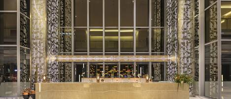 A modern hotel lobby with a reception desk, large windows, and decorative lighting.